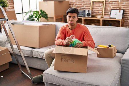 Photo for Hispanic man moving to a new home unpacking depressed and worry for distress, crying angry and afraid. sad expression. - Royalty Free Image