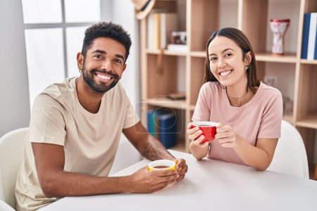 Photo for Man and woman couple sitting on table drinking coffee at home - Royalty Free Image