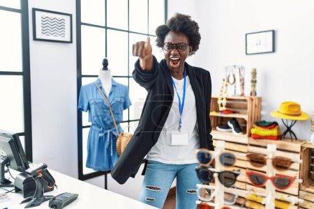 Foto de Mujer joven africana que trabaja como gerente en la boutique minorista señalando disgustado y frustrado a la cámara, enojado y furioso con usted - Imagen libre de derechos