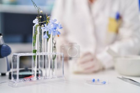 Photo for Middle age woman scientist pouring liquid on flowers at laboratory - Royalty Free Image