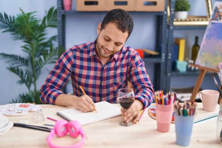Photo for Young man artist drinking wine drawing on notebook at art studio - Royalty Free Image