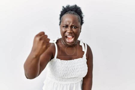 Photo for Young african woman standing over white isolated background angry and mad raising fist frustrated and furious while shouting with anger. rage and aggressive concept. - Royalty Free Image
