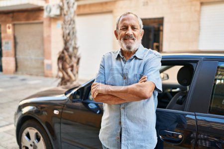 Photo for Senior grey-haired man smiling confident standing with ars crossed gesture by car at street - Royalty Free Image