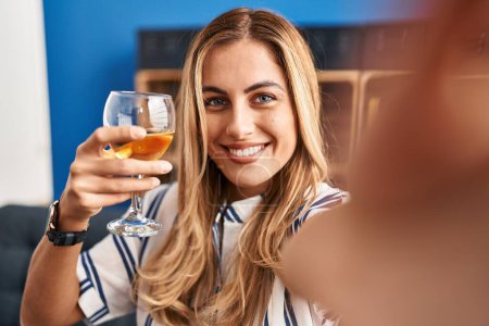Téléchargez les photos : Jeune femme blonde faire selfie par le smartphone boire du champagne à la maison - en image libre de droit