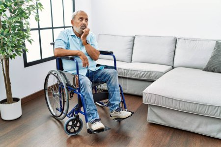 Photo for Handsome senior man sitting on wheelchair at the living room looking stressed and nervous with hands on mouth biting nails. anxiety problem. - Royalty Free Image