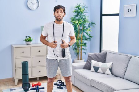 Téléchargez les photos : Handsome latin man wearing sportswear at home afraid and shocked with surprise expression, fear and excited face. - en image libre de droit