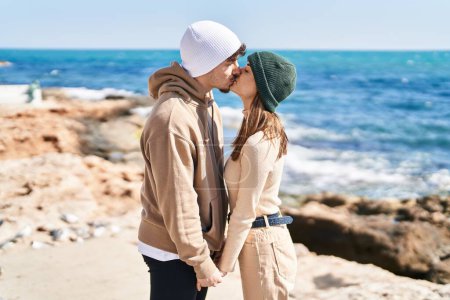 Foto de Mand and woman couple standing together kissing at seaside - Imagen libre de derechos