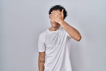 Photo for Hispanic man standing over isolated background covering eyes with hand, looking serious and sad. sightless, hiding and rejection concept - Royalty Free Image