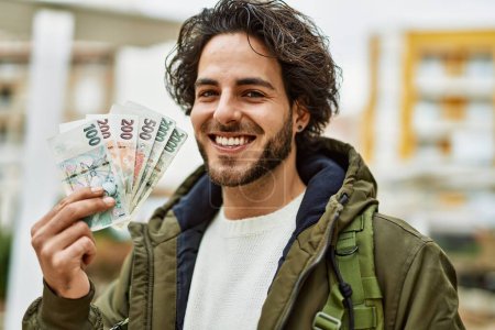 Photo for Handsome hispanic man holding czech crown banknotes at the city - Royalty Free Image