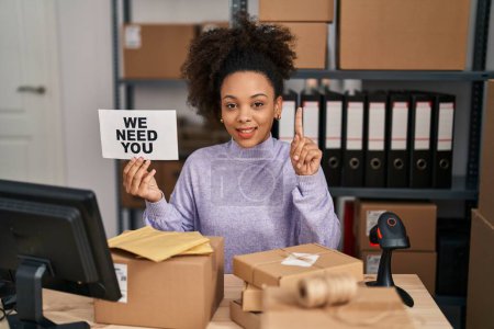 Foto de Young african american woman working at small business ecommerce holding banner surprised with an idea or question pointing finger with happy face, number one - Imagen libre de derechos