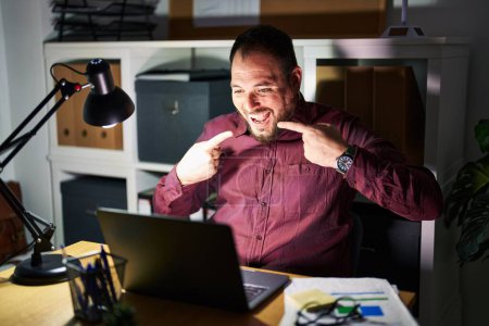 Téléchargez les photos : Plus size hispanic man with beard working at the office at night smiling cheerful showing and pointing with fingers teeth and mouth. dental health concept. - en image libre de droit