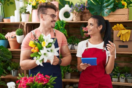 Téléchargez les photos : Fleuristes hommes et femmes tenant un bouquet de fleurs à l'aide d'un pavé tactile à la boutique de fleurs - en image libre de droit