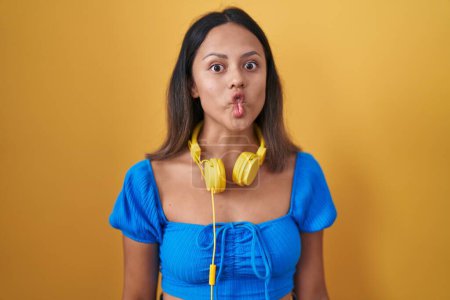 Téléchargez les photos : Hispanic young woman standing over yellow background making fish face with lips, crazy and comical gesture. funny expression. - en image libre de droit