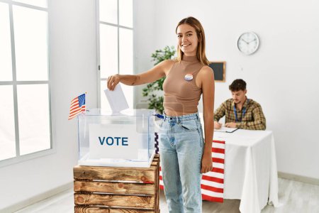 Foto de Joven votante americana poniendo voto en urnas en colegio electoral. - Imagen libre de derechos