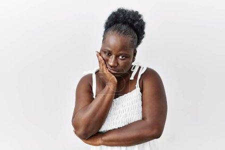 Téléchargez les photos : Jeune femme africaine debout sur fond blanc isolé pensant fatigué et ennuyé avec des problèmes de dépression avec les bras croisés. - en image libre de droit
