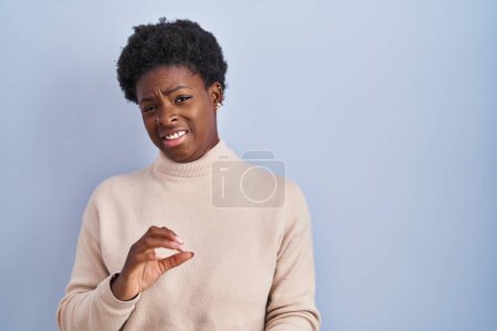 Foto de Mujer afroamericana de pie sobre fondo azul expresión disgustada, disgustada y temerosa haciendo cara de asco porque la reacción de aversión. con las manos levantadas - Imagen libre de derechos