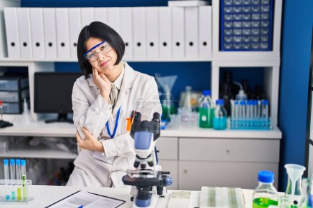 Téléchargez les photos : Jeune femme asiatique travaillant au laboratoire scientifique penser à la recherche fatigué et ennuyé avec des problèmes de dépression avec les bras croisés. - en image libre de droit