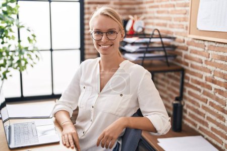 Téléchargez les photos : Jeune femme blonde travailleur d'affaires en utilisant l'écriture d'ordinateur portable sur le papier de rappel au bureau - en image libre de droit