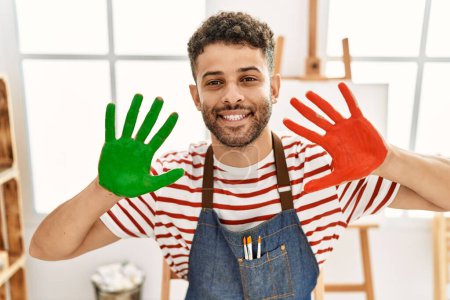 Photo for Young arab artist man smiling happy showing painted hands at art studio. - Royalty Free Image