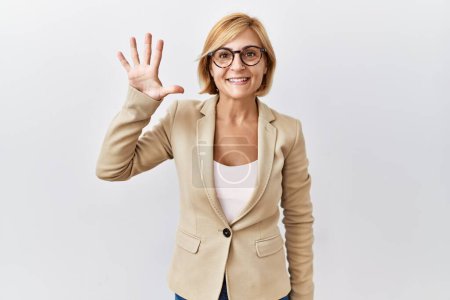 Téléchargez les photos : Moyen âge blonde femme d'affaires debout sur fond isolé montrant et pointant vers le haut avec les doigts numéro cinq tout en souriant confiant et heureux. - en image libre de droit