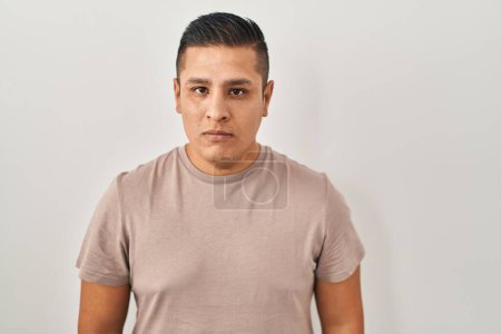 Téléchargez les photos : Jeune homme hispanique debout sur fond blanc détendue avec une expression sérieuse sur le visage. simple et naturel regardant la caméra. - en image libre de droit