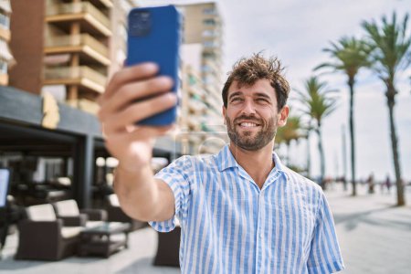 Téléchargez les photos : Jeune homme hispanique souriant heureux debout sur la promenade. - en image libre de droit