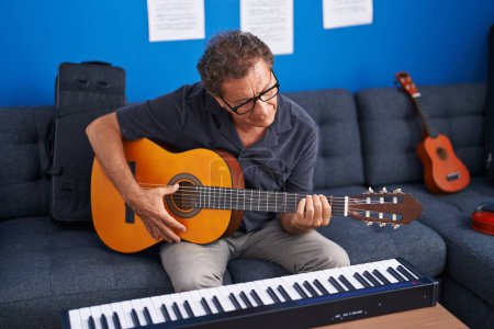 Photo for Middle age man musician playing classical guitar at music studio - Royalty Free Image