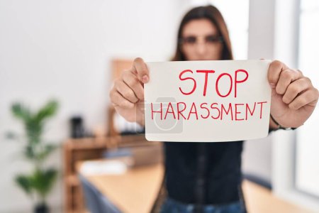 Photo pour Young beautiful hispanic woman business worker holding stop harassment message banner at office - image libre de droit