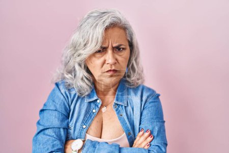 Photo for Middle age woman with grey hair standing over pink background skeptic and nervous, disapproving expression on face with crossed arms. negative person. - Royalty Free Image