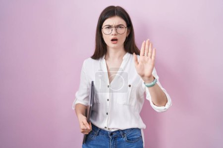 Photo for Young caucasian woman holding laptop doing stop gesture with hands palms, angry and frustration expression - Royalty Free Image