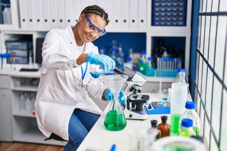Photo for African american woman scientist pouring liquid on test tube at laboratory - Royalty Free Image