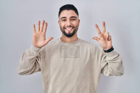 Photo for Young handsome man standing over isolated background showing and pointing up with fingers number eight while smiling confident and happy. - Royalty Free Image