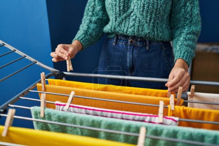 Téléchargez les photos : Young beautiful hispanic woman hanging clothes on clothes on clothesline at laundry room - en image libre de droit
