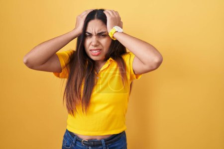 Photo for Young arab woman standing over yellow background suffering from headache desperate and stressed because pain and migraine. hands on head. - Royalty Free Image