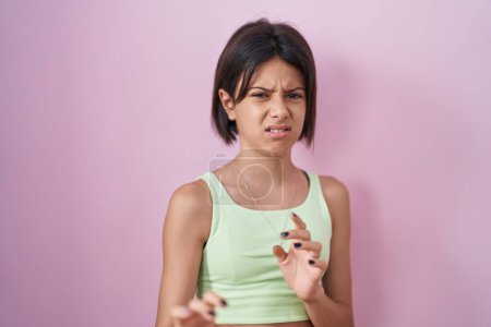 Photo for Young girl standing over pink background disgusted expression, displeased and fearful doing disgust face because aversion reaction. - Royalty Free Image