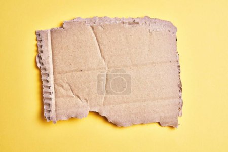 Foto de Una pieza rasgada de material de cartón sobre un fondo amarillo aislado - Imagen libre de derechos