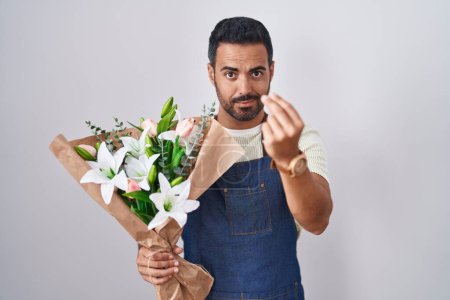Téléchargez les photos : Homme hispanique avec barbe travaillant comme fleuriste faire geste italien avec la main et les doigts expression confiante - en image libre de droit