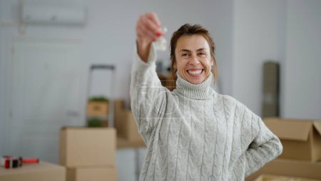 Foto de Mujer hispana de mediana edad sonriendo confiada sosteniendo la llave de una nueva casa en un nuevo hogar - Imagen libre de derechos
