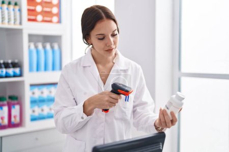 Photo for Young woman pharmacist scanning pills bottle at pharmacy - Royalty Free Image