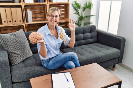 Photo for Beautiful woman working at consultation office doing ok sign with fingers, smiling friendly gesturing excellent symbol - Royalty Free Image