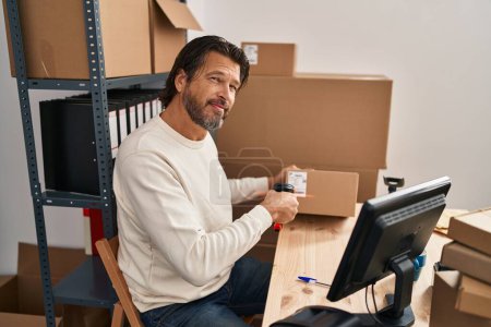 Foto de Hombre de mediana edad comercio electrónico empresa trabajador paquete de escaneo en la oficina - Imagen libre de derechos