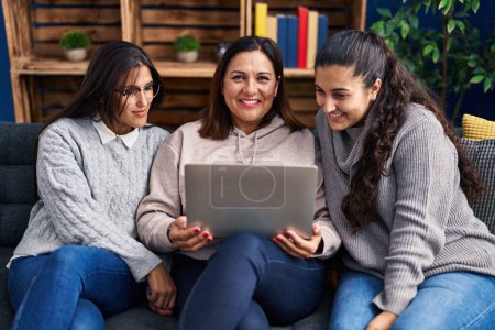Photo for Three woman using laptop sitting on sofa at home - Royalty Free Image