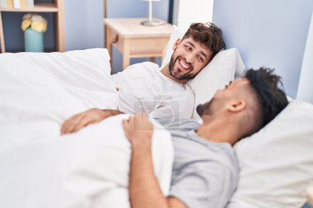 Téléchargez les photos : Jeune couple souriant confiant couché sur le lit dans la chambre à coucher - en image libre de droit