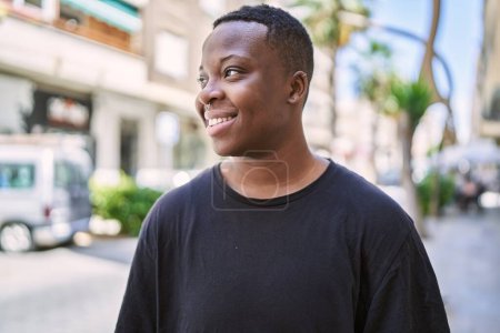 Téléchargez les photos : Jeune transgenre afro-américain souriant confiant dans la rue - en image libre de droit