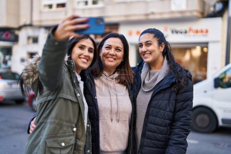 Photo for Three woman mother and daughters make selfie by the smartphone at street - Royalty Free Image