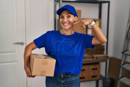 Téléchargez les photos : Middle age brunette woman working wearing delivery uniform and cap smiling cheerful showing and pointing with fingers teeth and mouth. dental health concept. - en image libre de droit