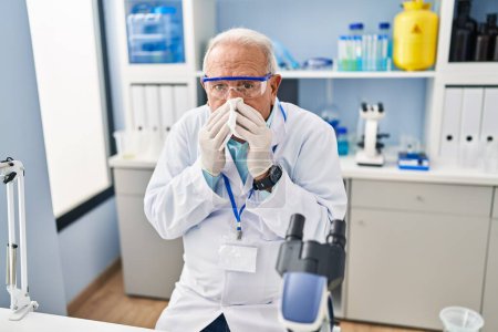 Foto de Hombre mayor vistiendo uniforme científico usando servilleta en laboratorio - Imagen libre de derechos