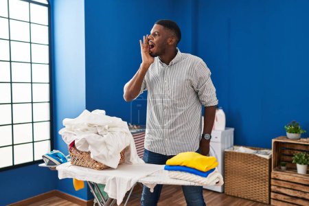 Photo for African american man ironing clothes at home clueless and confused with open arms, no idea and doubtful face. - Royalty Free Image