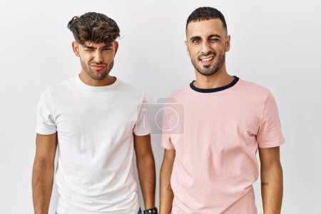 Photo for Young gay couple standing over isolated background winking looking at the camera with sexy expression, cheerful and happy face. - Royalty Free Image