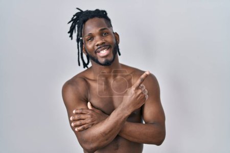 Photo for African man with dreadlocks standing shirtless over isolated background smiling happy pointing with hand and finger to the side - Royalty Free Image